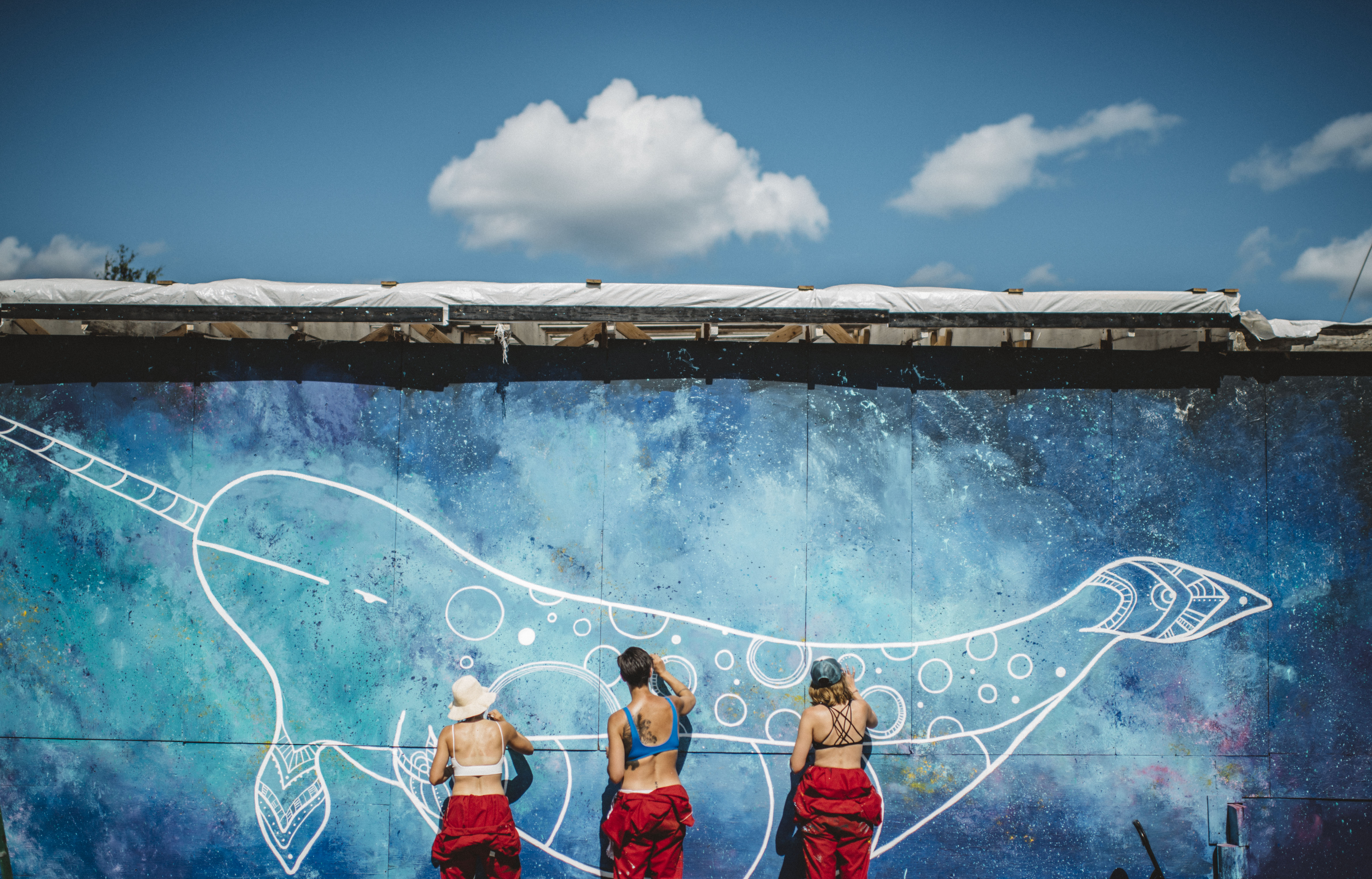 Three Yellowknife artists paint a narwhal mural at the Festival